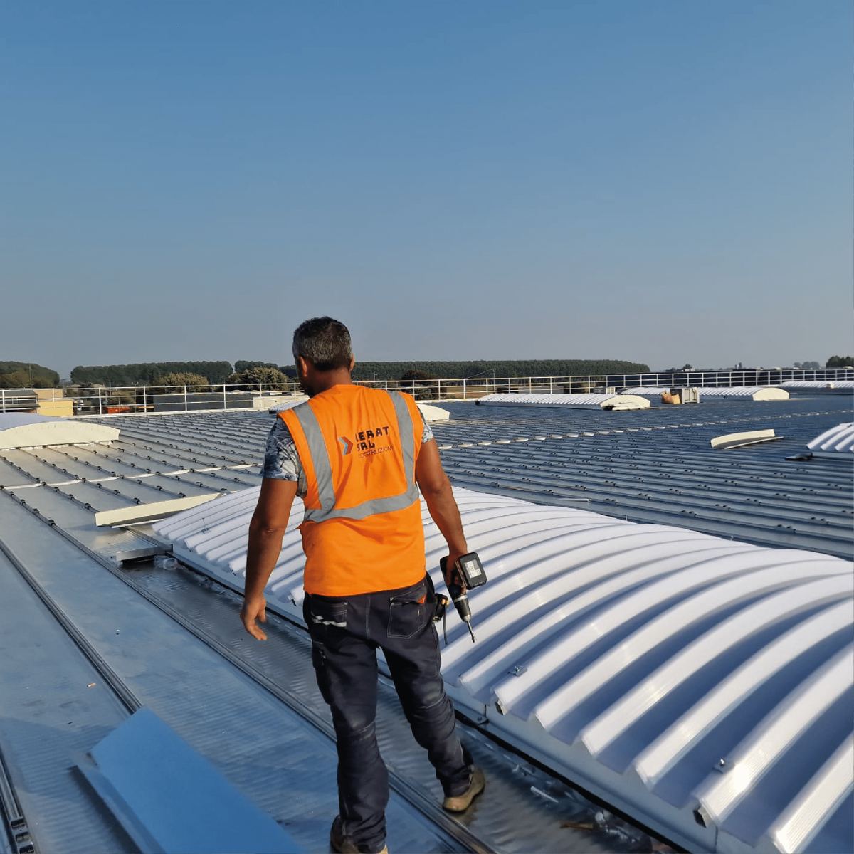 Tecnico al lavoro su una copertura industriale con lucernari a volta
